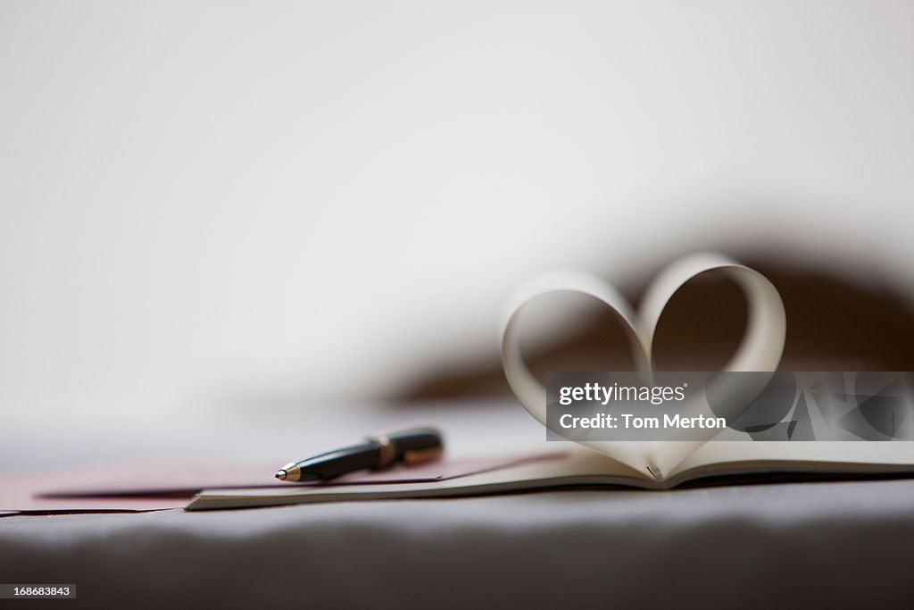 Pen and pages of notebook forming heart-shape