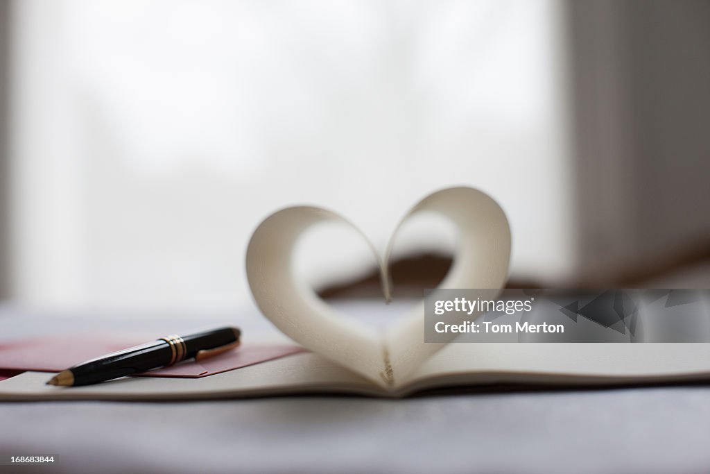 Pen and pages of notebook forming heart-shape