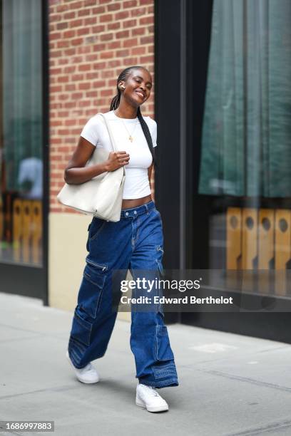 Model wears a white cropped t-shirt, blue cargo jeans pants, white sneakers shoes, a white bag, outside Tibi , during New York Fashion Week, on...