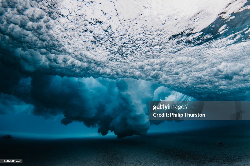 Underwater view beneath a breaking wave exploding with high contrast dispersed water pattern using a flash