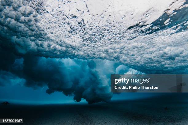 underwater view beneath a breaking wave exploding with high contrast dispersed water pattern using a flash - bubble burst stock pictures, royalty-free photos & images