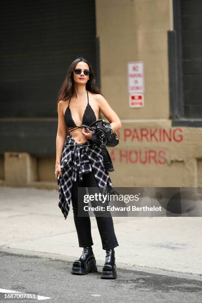 Guest wears sunglasses, black bras, a checked shirt over the waist, black jeans, leather shoes, outside Tibi , during New York Fashion Week, on...