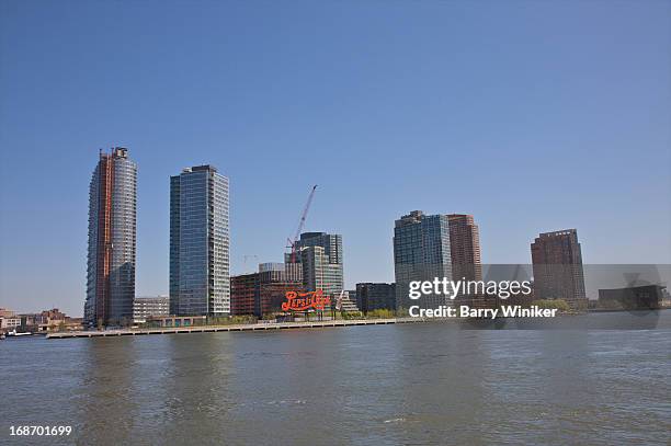 sign and new buildings near water. - long island city stock pictures, royalty-free photos & images