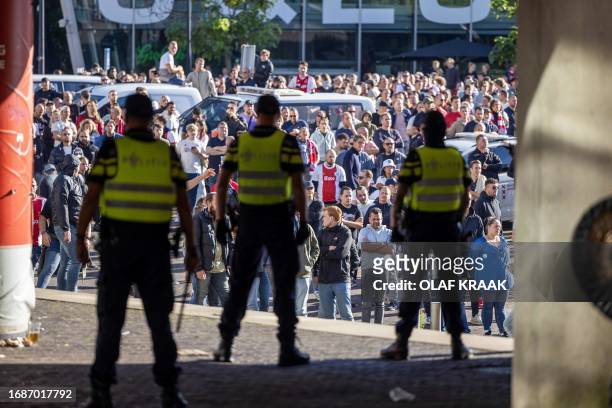 Police officers stand guard in front of Ajax' supporters outside the Johan Cruijff Arena after the Dutch Eredivisie football match between Ajax...
