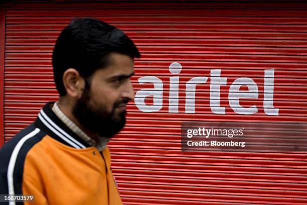 Man walks past a shutter of a closed store displaying the Bharti Airtel Ltd. Logo in Srinagar, India, on Sunday, May 12, 2013. Indian inflation eased...