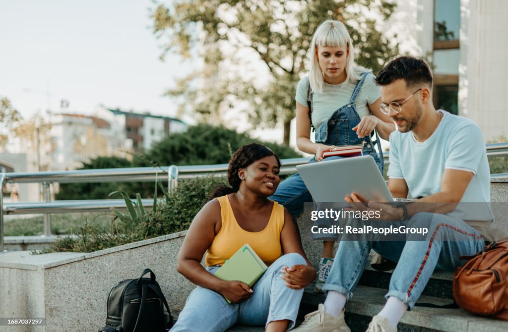 A multiracial group of college friends looking at a laptop