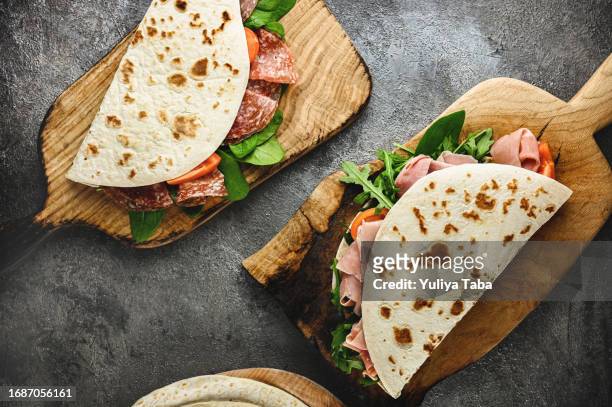 piadina on a wooden cutting board. - wrapped burrito stock pictures, royalty-free photos & images