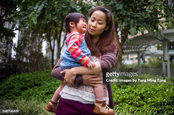 Toddler girl crying in mom's arms in park