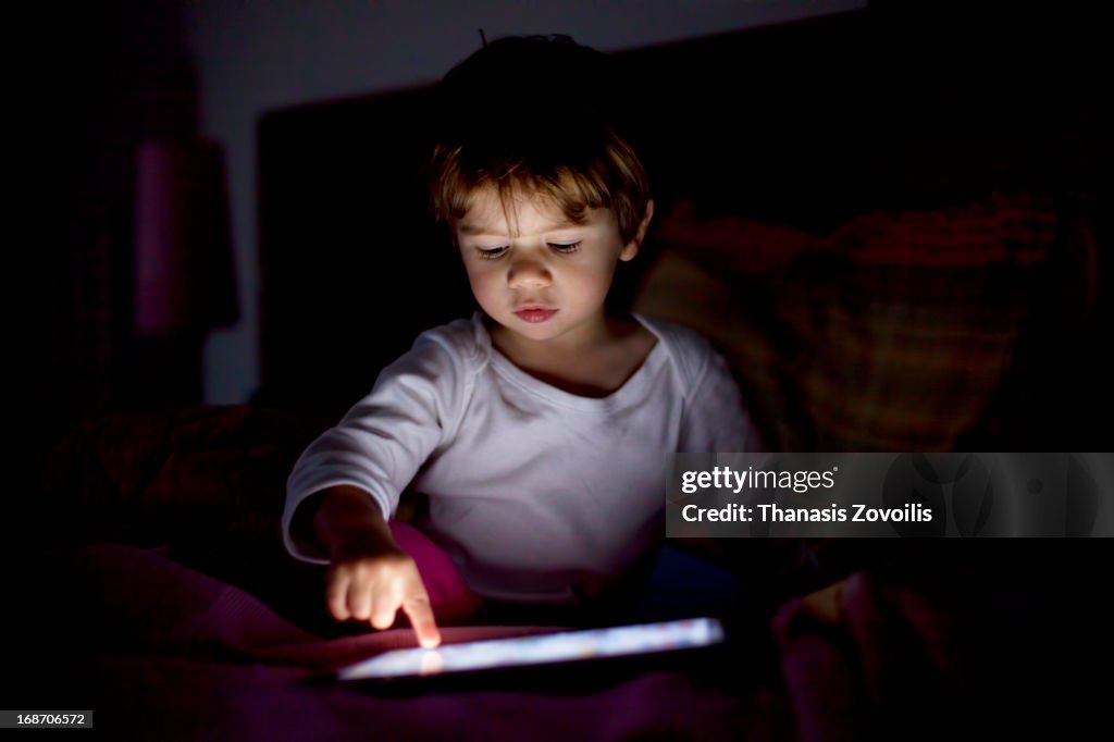 Small boy looking at a tablet in the dark