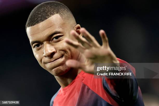 Paris Saint-Germain's French forward Kylian Mbappe waves as he warms up before the French L1 football match between Paris Saint-Germain and Olympique...