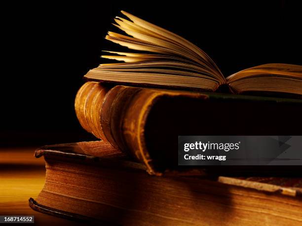stack of rustic, antique books on dark background - old book stock pictures, royalty-free photos & images