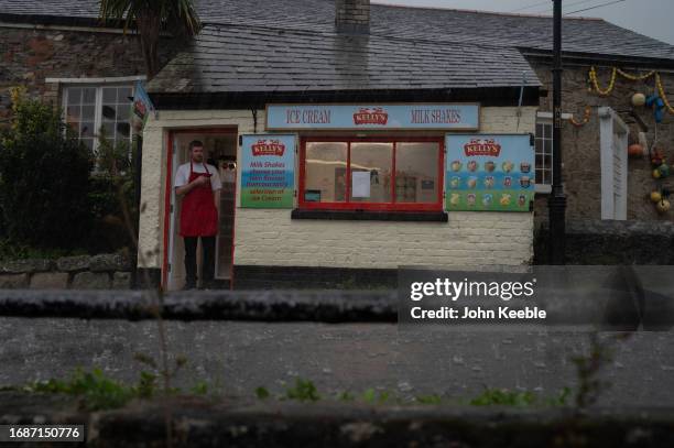 Vendor watches a heavy rain downpour from an Ice Cream shop in Charlestown on September 17, 2023 in St Austell, Cornwall, United Kingdom.