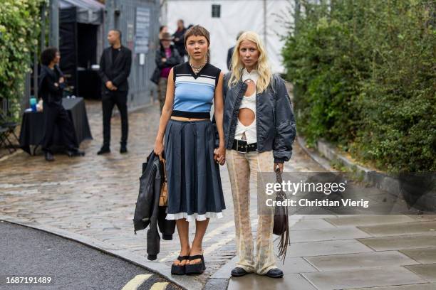 Emma Fridsell wears grey skirt, blue black top & Laura Tønder wears white cut out top, grey jacket, beige transparent pants outside Holzweiler during...