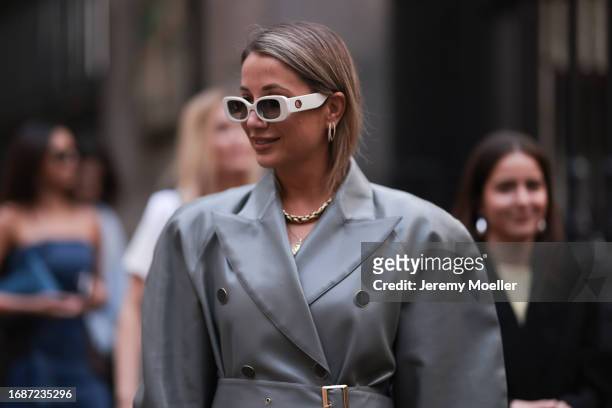 Fashion Week Guest was seen wearing white shades, a yellow gold chain, earrings and an oversized silver coat with grey buttons before ERDEM Fashion...