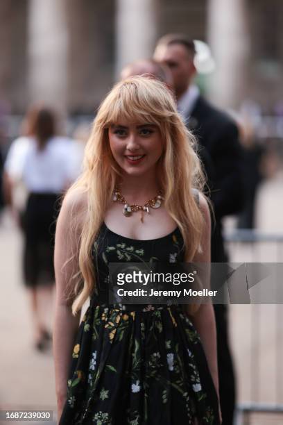 Kathryn Newton was seen wearing a chain with stones and ornaments as well as a black dress with green and yellow flowers on it before ERDEM Fashion...