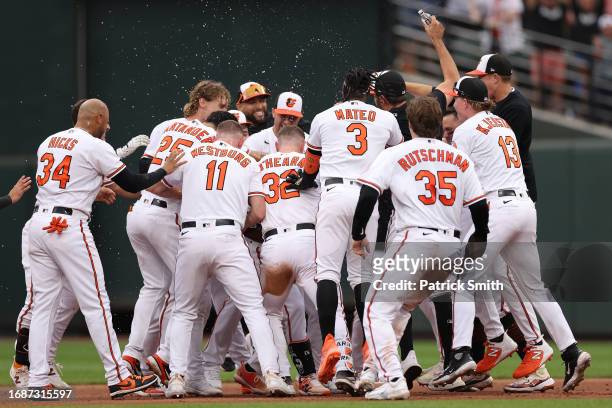 Cedric Mullins of the Baltimore Orioles celebrates with teammates after hitting a sacrifice RBI against the Tampa Bay Rays during the eleventh inning...