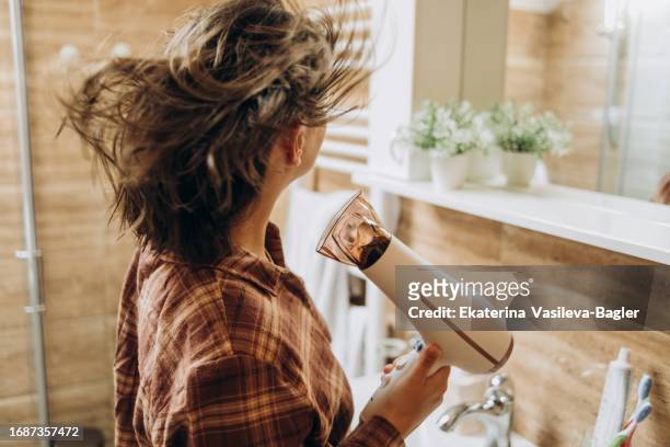 happy woman drying long hair in bathroom - hair dryer ストックフォトと画像