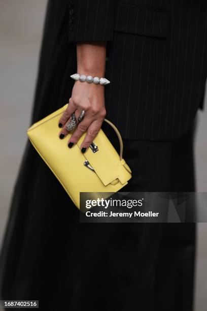 Corina Mihaila Larpin is seen wearing bracelet and ring from Stéfère, a black pinstripe blazer with long tulle back from Monse and the Kelly bag from...
