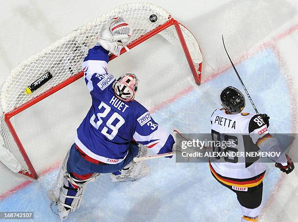 French goalkeeper Cristobal Huet and Germany's forward Daniel Pietta rush to get a puc during a preliminary round game France vs Germany of the IIHF...