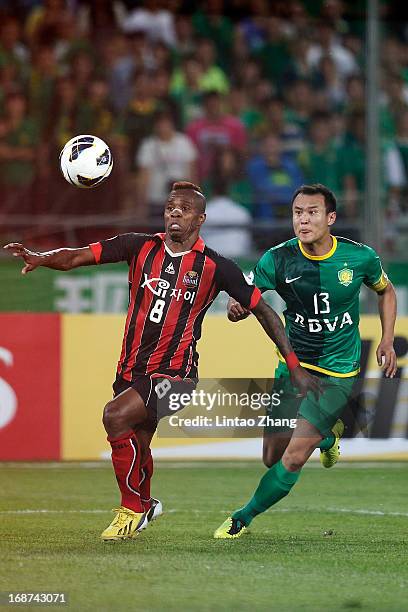 Adilson of Seoul FC challenges Yunlong Xu of Beijing Guoan during the AFC Champions League Round of 16 match between Beijing Guoan and Seoul FC at...