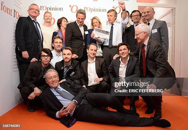 French journalist Nicolas Beytout poses with his team and a copy of the first hardcopy edition of the daily newspaper "L'Opinion" during the launch...