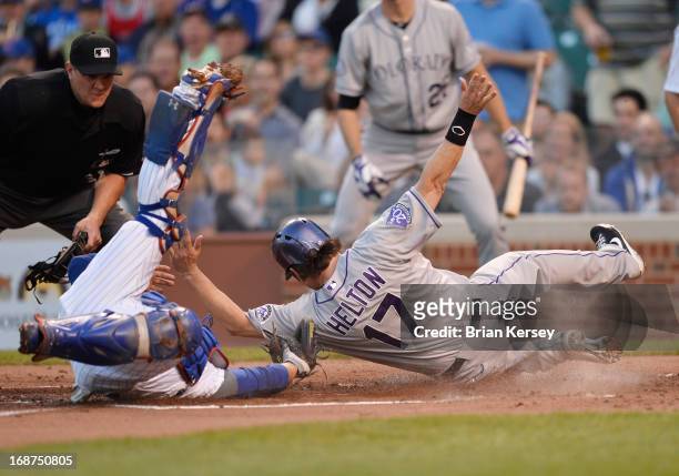 Catcher Welington Castillo of the Chicago Cubs tags out Todd Helton of the Colorado Rockies at home plate after he tried to score on a single hit by...