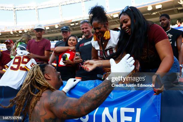 Chase Young of the Washington Commanders hugs a fan after his team's 35-33 win against the Denver Broncos at Empower Field At Mile High on September...