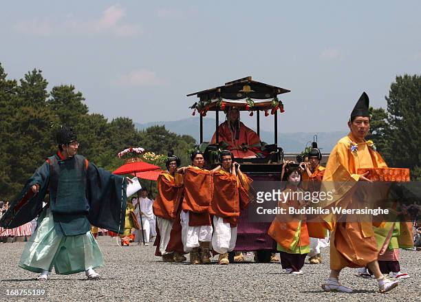 People dressed in traditional costumes carry Maiko Nagase , sitting in a portable shrine in the procession of the Aoi Festival at the Imperial Palace...