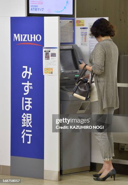 Woman uses a Mizuho Bank ATM on a concourse in Tokyo on May 15, 2013. Mizuho Financial Group said on May 15 that its net profit in the year to March...