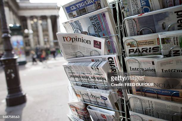 Copy of the newspaper "L'opinion" is pictured amongst other newspapers in a newsstand on May 15, 2013 in Paris. The newspaper, also available online,...