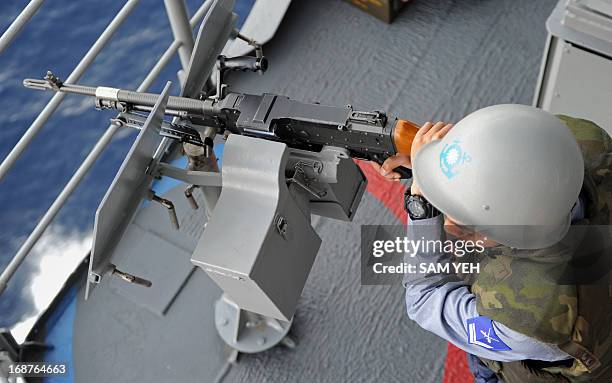 Taiwan sailor operates a machine gun on a Kidd-class destroyer as it patrols in the Taiwan strait during a drill on May 15, 2013 aimed at defending...