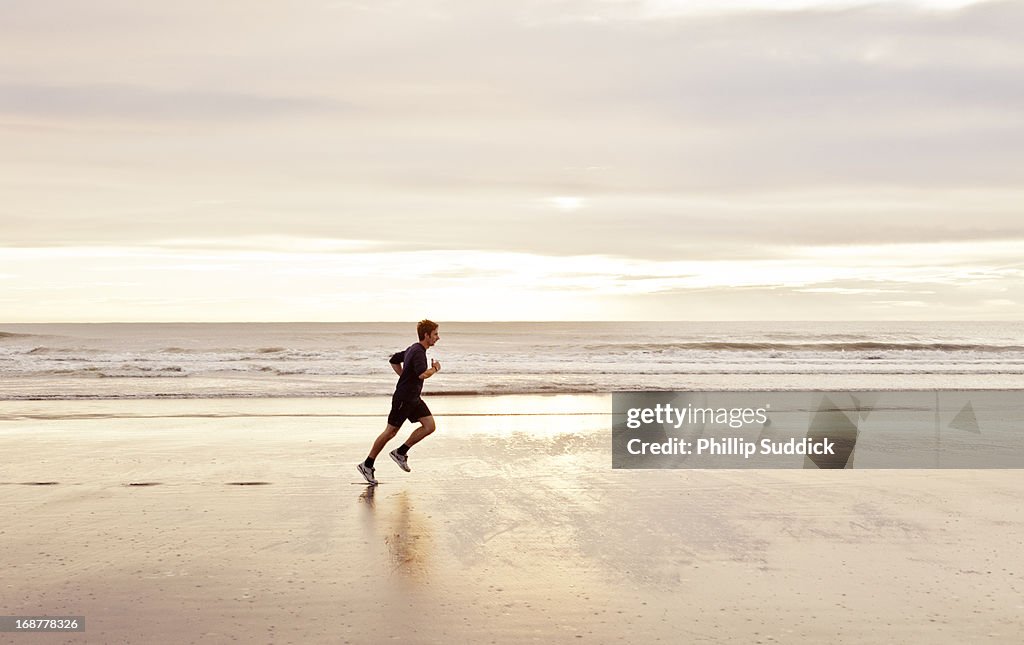 Man jogging on beach at sunrise