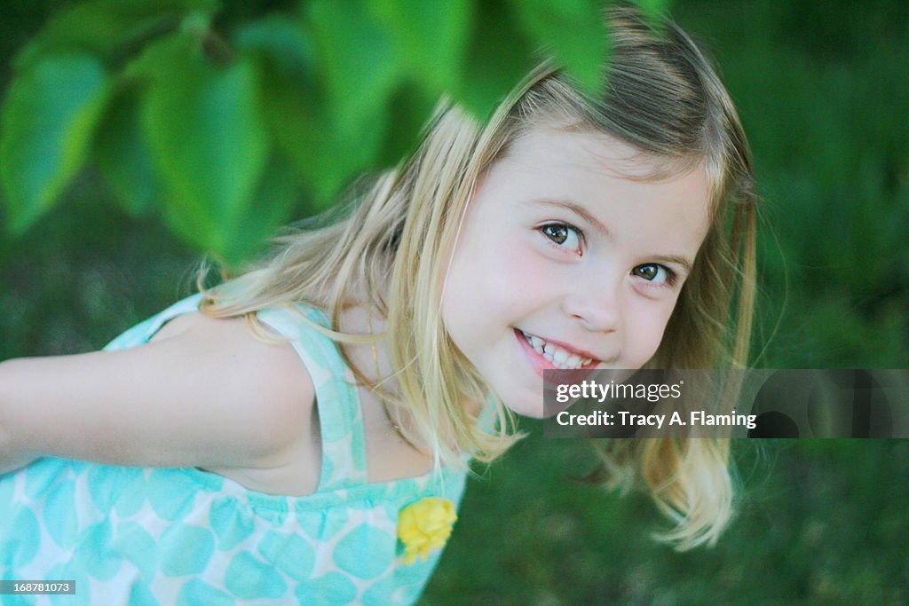 Girl peeking out from leaves.