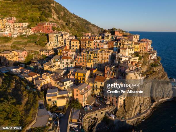 manarola traditional typical italian village in national park cinque terre, colorful multicolored buildings houses on rock cliff, fishing boats on water, sunset, la spezia, liguria, italy - manarola stock pictures, royalty-free photos & images