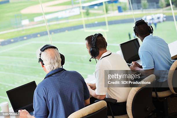 sportscasters frente y ocasiona un juego de fútbol americano en press box - periodismo fotografías e imágenes de stock