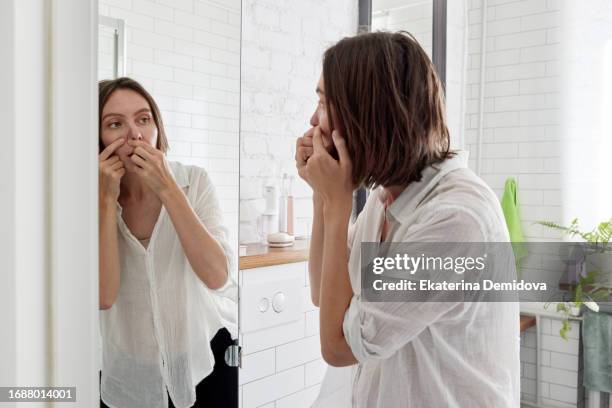 women looking for a pimple in bathroom at home - hautfleck stock-fotos und bilder