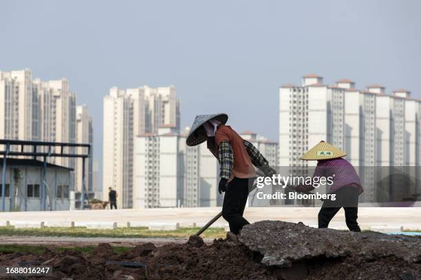 Workers in front of residential buildings under construction at the Phoenix Palace project, developed by Country Garden Holdings Co., in Heyuan,...