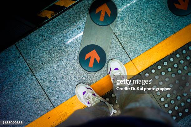 arrowhead sign on the floor of subway -yellow line - looking down at shoes stock pictures, royalty-free photos & images