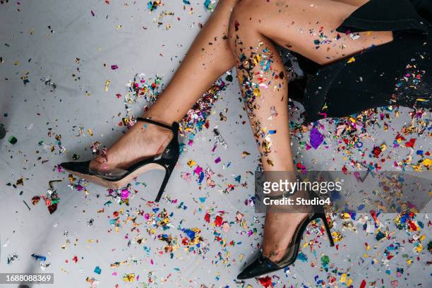 exuding timeless charm, a well-dressed lady embraces the joy of the holiday season in a studio shot, surrounded by confetti, as she pops open a champagne bottle to mark the occasion - black dress party stockfoto's en -beelden