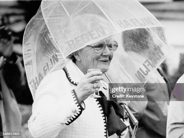 Queen Juliana of the Netherlands uses an umbrella to shield herself from the rain during a garden reception at Soestdijk Palace, 28th May 1979.