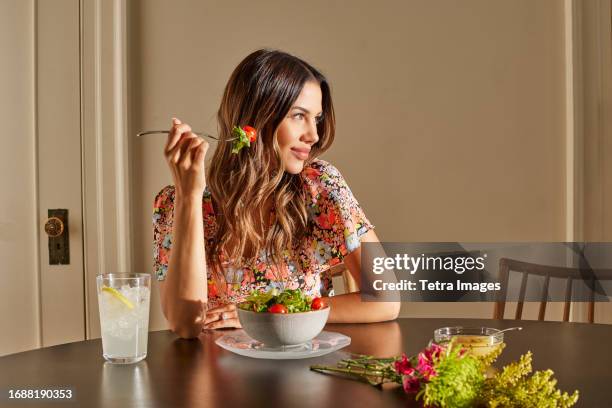 Smiling woman enjoying salad at table at home