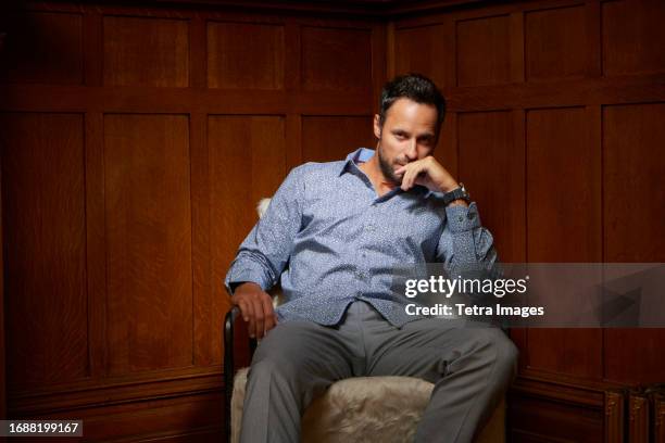 portrait of mid adult man sitting on chair - grey shirt stock pictures, royalty-free photos & images