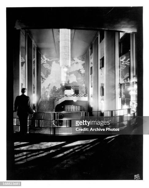 Man, seen from behind, leans against the railing of the gallery in the lobby of Radio City Music Hall in New York City, 1930s.