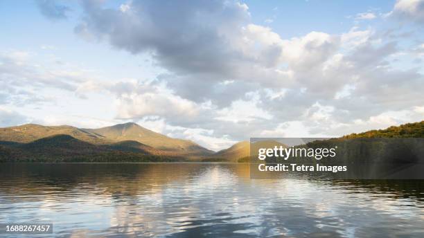 lake placid reflecting whiteface mountain and clouds - lake placid stock pictures, royalty-free photos & images