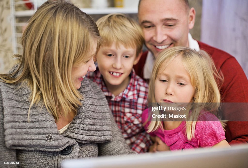 Happy family of four with laptop at home
