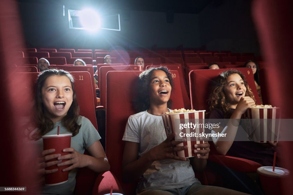 Glückliche Mädchen, die einen überraschenden Film im Kino sehen.
