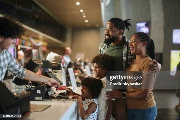 happy black family buying movie tickets in cinema. - movie counter stock pictures, royalty-free photos & images