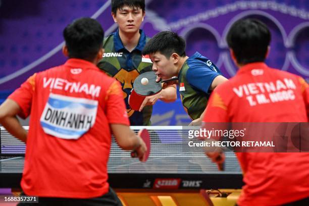 Singapore's Clarence Chew Zhe Yu and teammate Zeng Jian hit a return against Vietnam's Tran Mai Ngoc and Dinh Anh Hoang in their mixed doubles table...