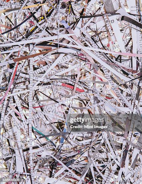 a pile of long thin shredded pieces of printed newspapers. - shredded newspaper stock pictures, royalty-free photos & images