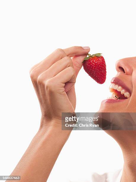 lächelnde frau isst erdbeere - erdbeeren freisteller stock-fotos und bilder